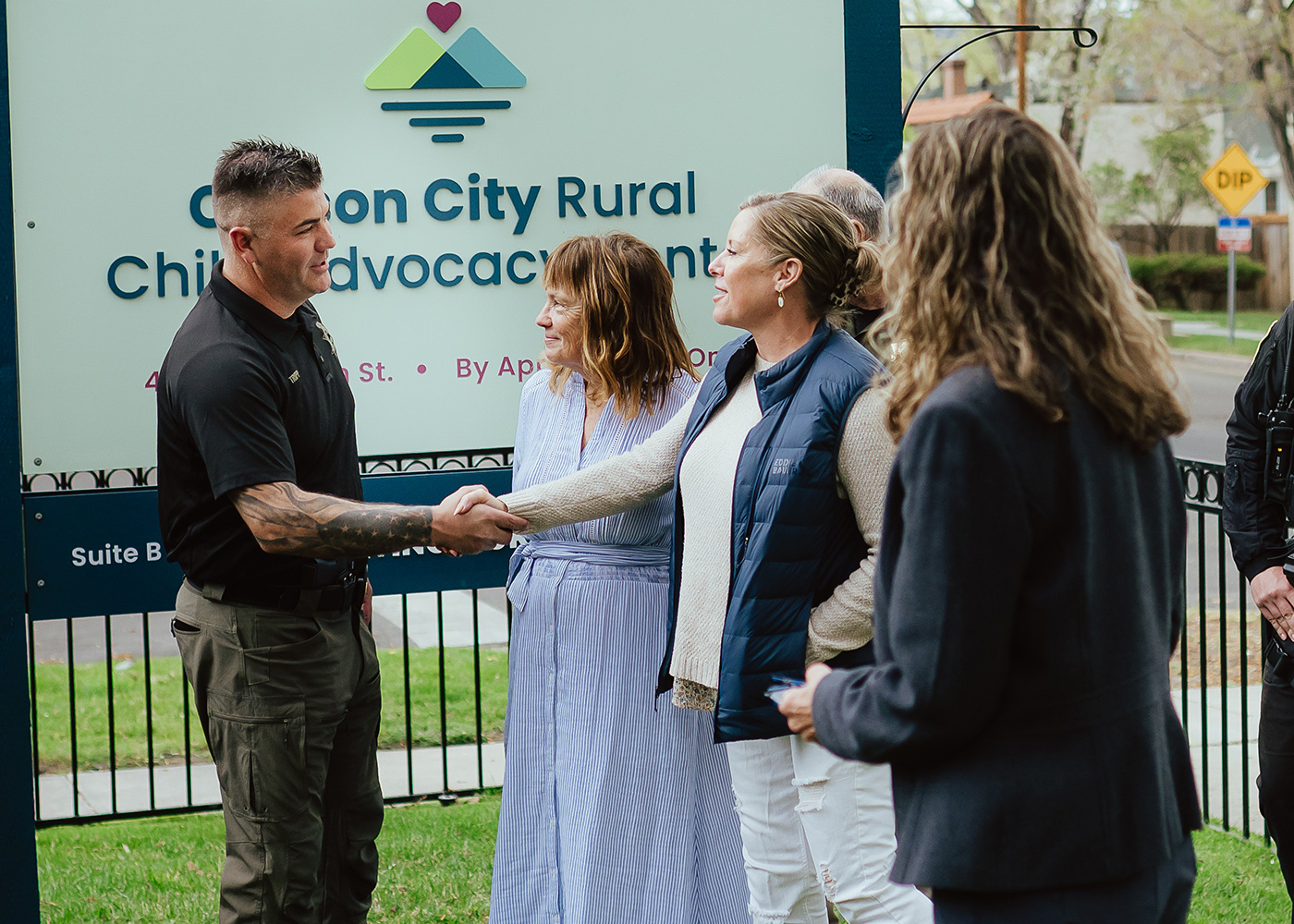 sheriff and community members shaking hands in front of a child advocacy center